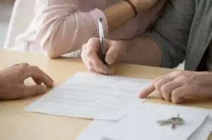man signing paper with wife next to him