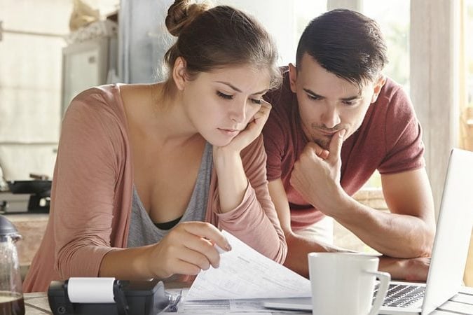couple looking at finances with computer open and coffee