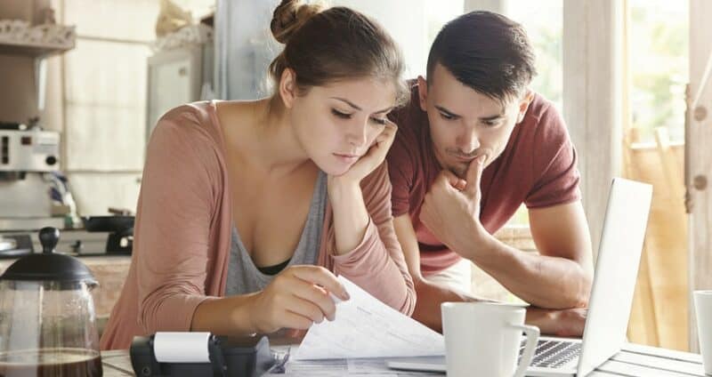 couple looking at finances with computer open and coffee
