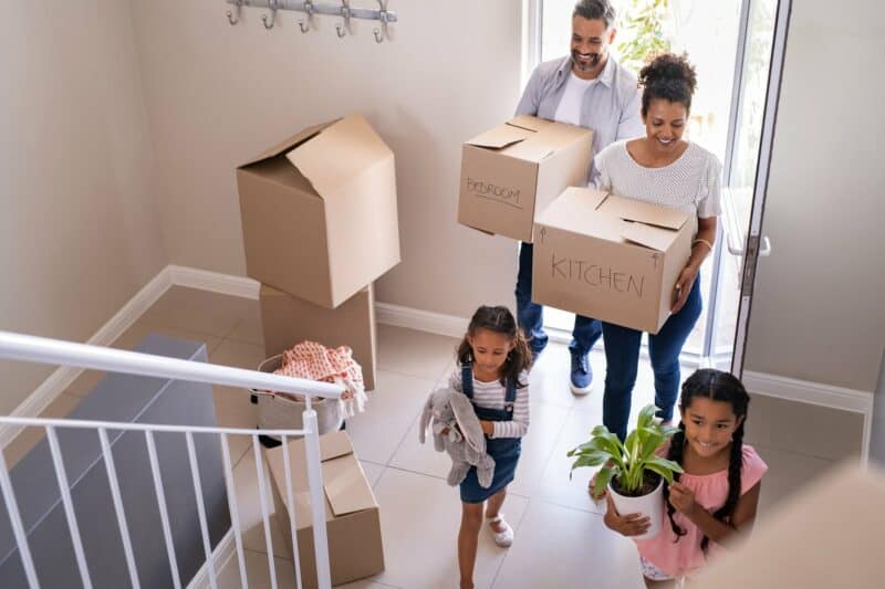 family moving into home with boxes, plants, and toys
