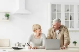 smiling couple in home on laptop