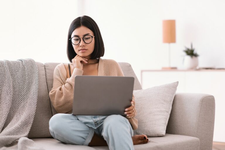 Woman reading laptop on her couch